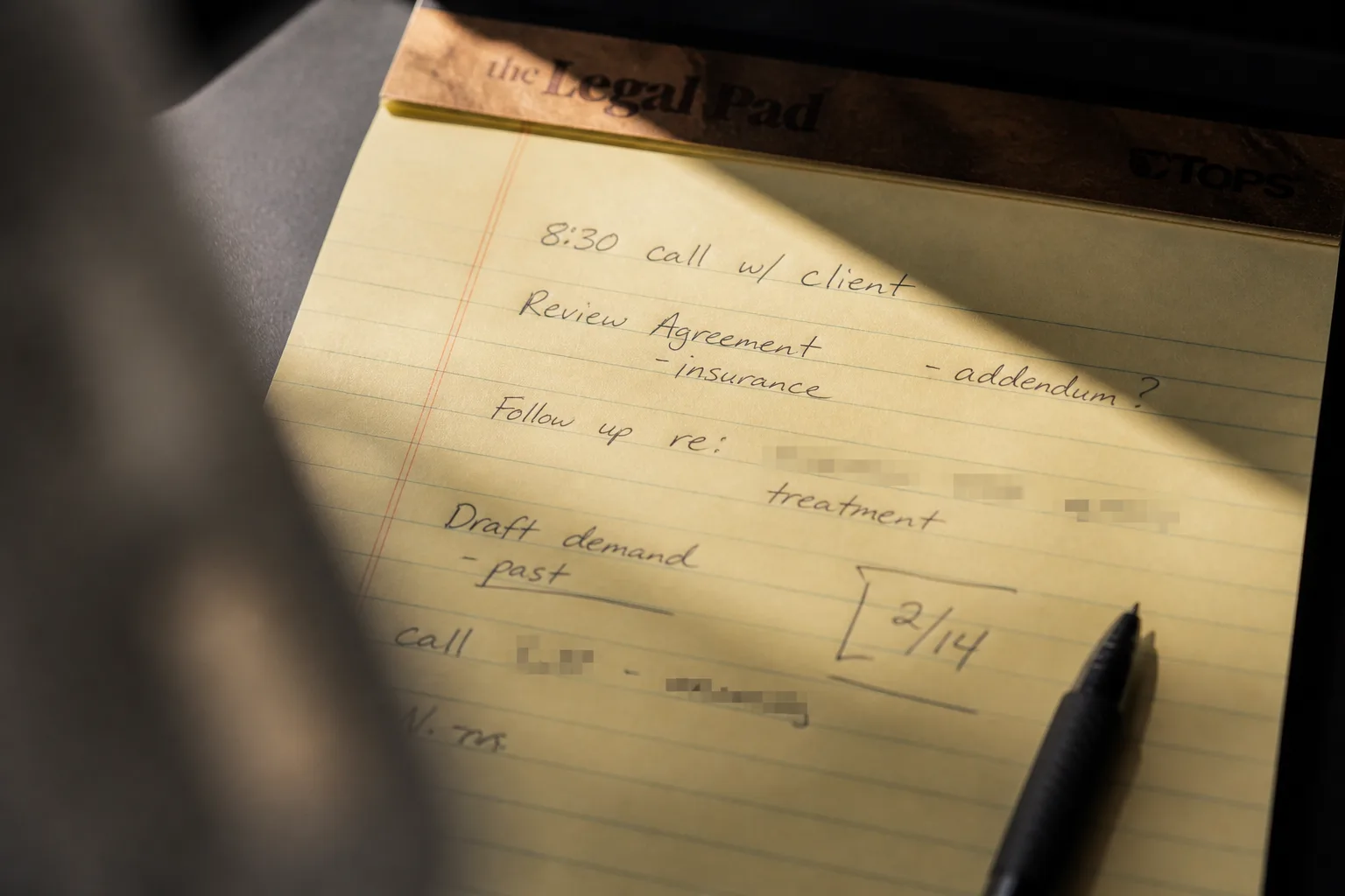 A legal pad with handwritten client notes — call times, agreement reviews, follow-ups — the kind of task list that lives on paper and disappears when the person carrying it leaves.